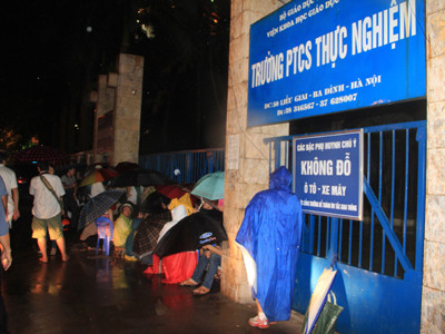 Ngay từ 11h đêm 10-5, nhiều người đã đội mưa ngồi trước cổng trường PTCS Thực Nghiệm để chờ mua tờ đăng ký thi cho con em mình
