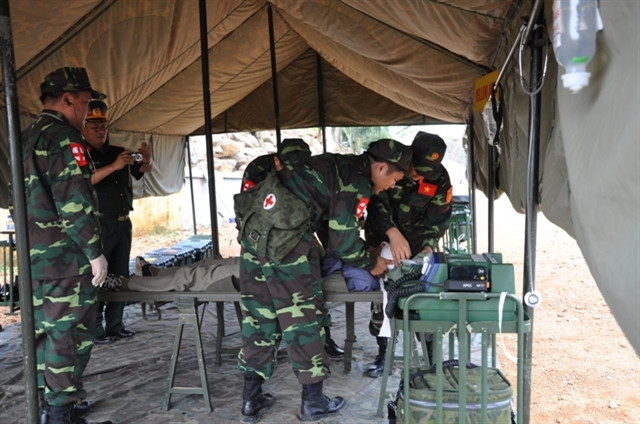 Trong khu lều dã chiến, các bác sĩ quân y tiến hành khám, chữa cho người bị thương 