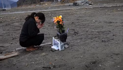 Cô Mika Hashikai, 37 tuổi đang cầu nguyện cho người cha quá cố đã mất tích trong thảm họa năm 2011. Cô Mika Hashikai, 37 tuổi đang cầu nguyện cho người cha quá cố đã mất tích trong thảm họa năm 2011