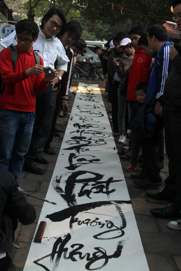 Nhiều người theo dõi việc thực hiện bức thư pháp có khổ dài rộng này