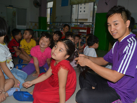Thầy Nguyễn Hữu Toàn đang buộc tóc cho một bé trong lớp