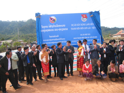 Anh Nguyễn Đắc Vinh, anh Vilayvong Bouddakham cùng cán bộ Đoàn, thanh niên hai nước trước tấm biển Làng Hữu nghị Thanh niên biên giới Lào – Việt