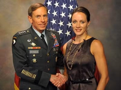Ông David Petraeus và bà Paula Broadwell bắt tay trước quốc kỳ Mỹ