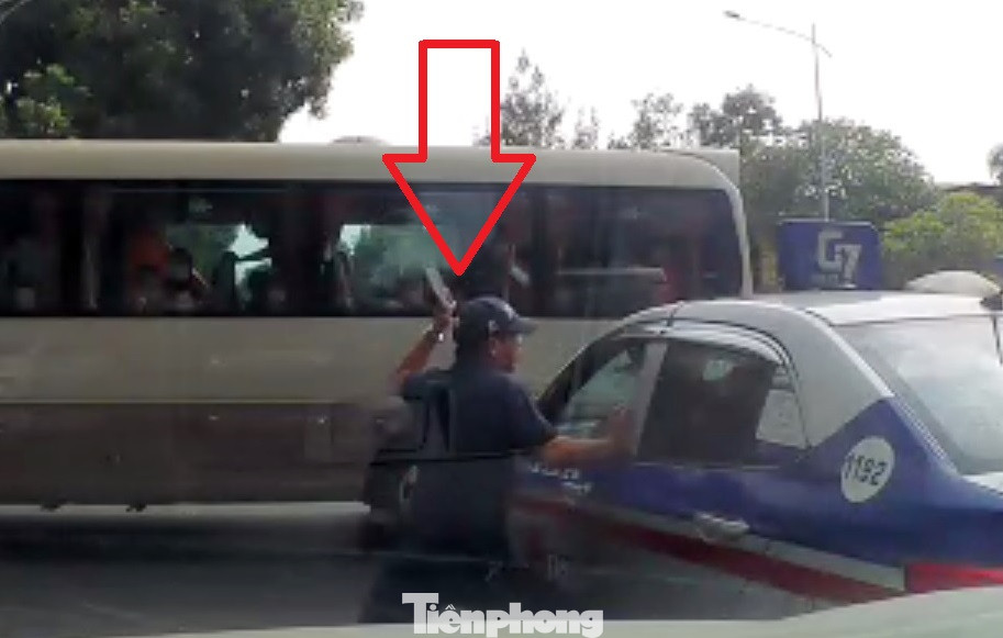Sau đó tài xế xe khách 29B-00732 đã nhảy xuống đường chạy đến cầm theo vật dụng tấn công tài xế taxi. Ảnh cắt từ clip.