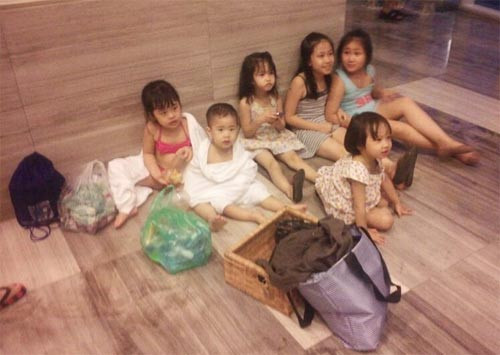 Nhiều trẻ em phải mặc nguyên đồ bơi ngồi chờ phòng gửi đồ mở cửa. Ảnh: K.N