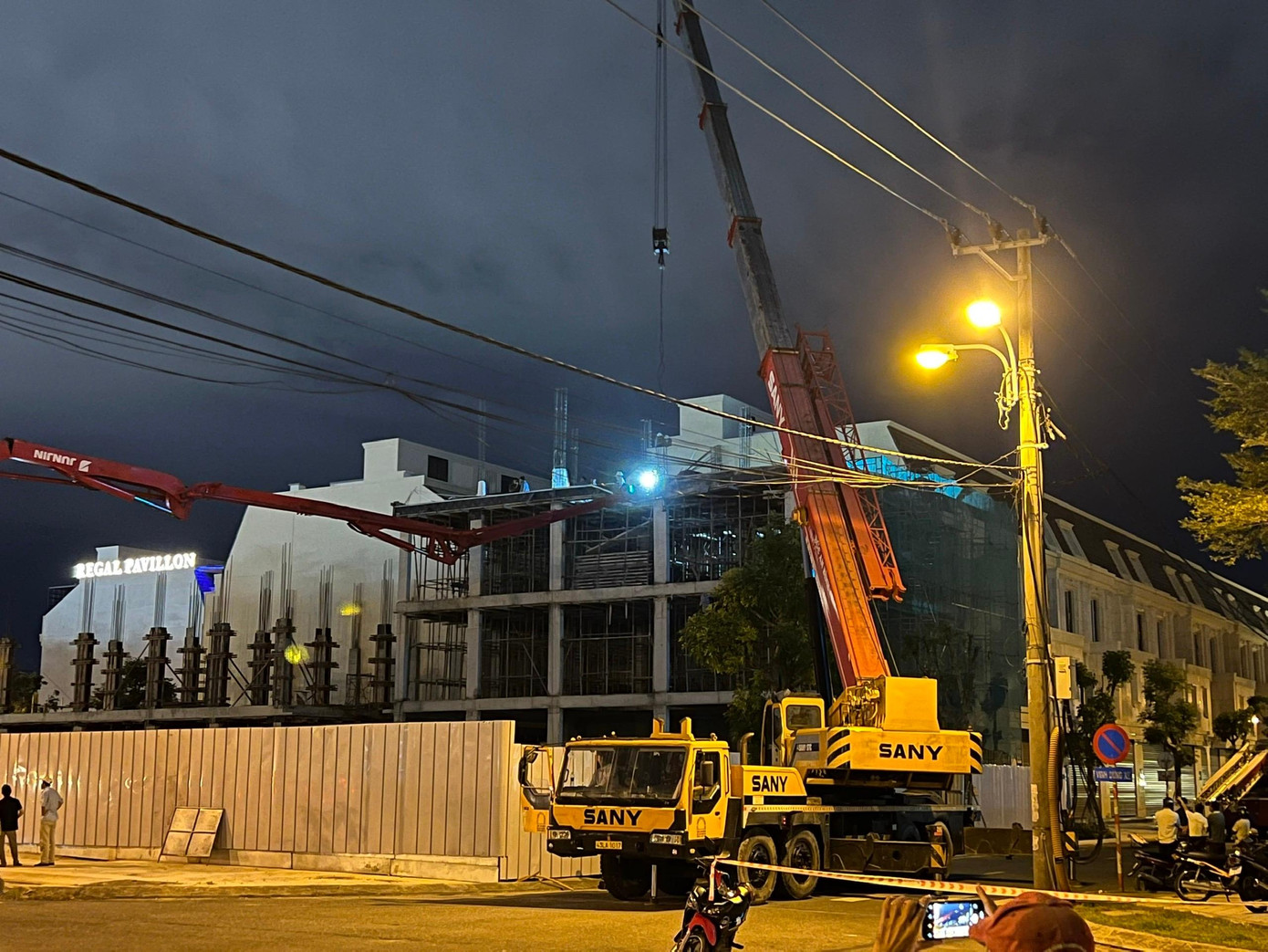 Lực lượng cứu nạn xác định ông Trương Minh D. (SN 1978, trú xã Hoà Nhơn, huyện Hoà Vang, TP Đà Nẵng) và ông Trương Văn A. (SN 1988, trú xã Hoà Phong, huyện Hòa Vang) là 2 công nhân điều khiển cần bơm của xe bơm bê tông. Trong ảnh: lực lượng chức năng phải huy động xe cẩu cỡ lớn nâng cần trục phun bê tông bị gãy gập để đưa nạn nhân ra ngoài.