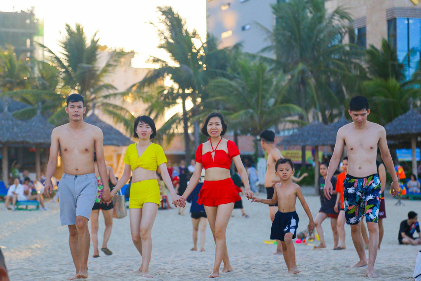 Nhóm du khách là gia đình ba thế hệ dắt tay nhau đi tắm biển.