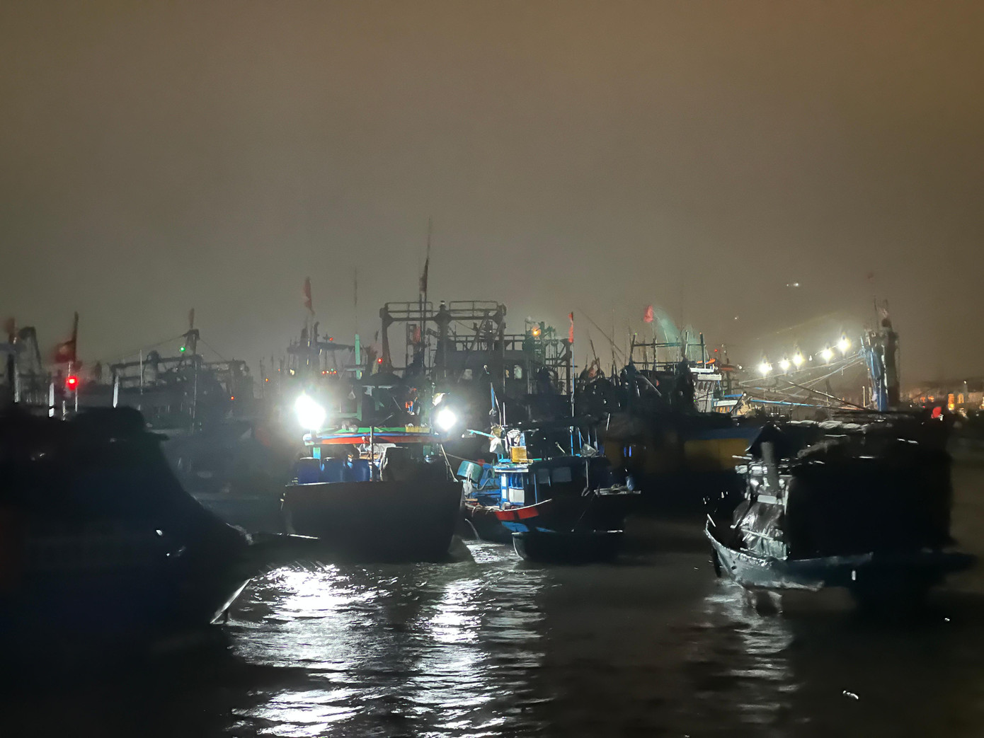Nhiều con thuyền vẫn đỏ đèn đêm khuya, ngư dân trên thuyền tất bật tát nước xuống. Nhiều con thuyền vẫn đỏ đèn đêm khuya, ngư dân trên thuyền tất bật tát nước xuống.