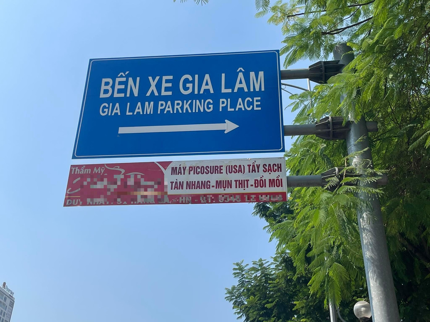 Biển báo chỉ dẫn vào bến xe Gia Lâm trên đường Nguyễn Văn Cừ, Long Biên, Hà Nội được gắn với biển quảng cáo dịch vụ chữa các bệnh ngoài da của một thẩm mỹ viện.