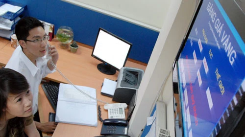 Nhân viên phòng kinh doanh Công ty cổ phần Vàng bạc đá quý Phú Nhuận luôn cập nhật giá trong ngày cùng với giá vàng thế giới. Ảnh: T.Đạm (Tuổi Trẻ)