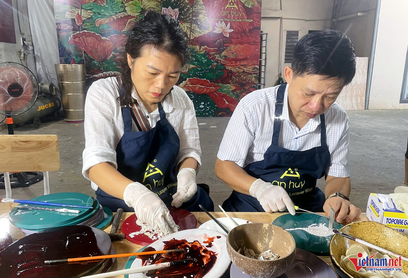 Khách du lịch trải nghiệm làm sản phẩm sơn mài ngay tại xưởng, dưới sự hướng dẫn của những người thợ Hạ Thái. Ảnh: Ngọc Hà