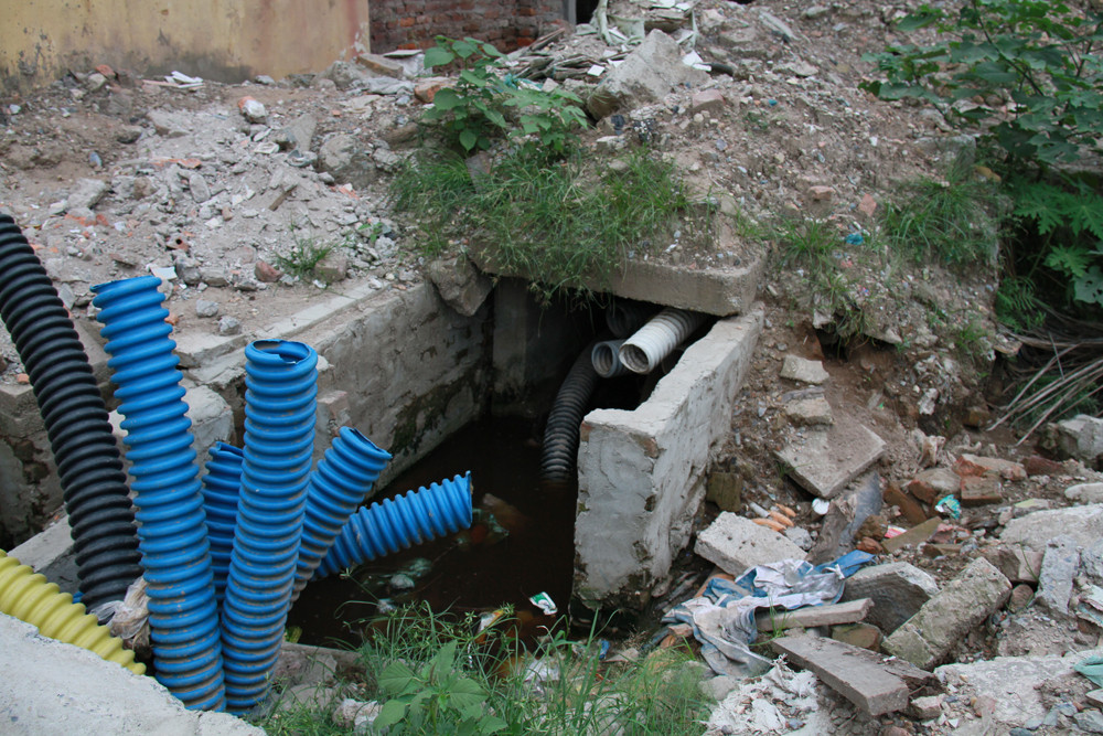 Hố cống ngập nước thải, không che chắn ngay cổng trường Tiểu học Thái Thịnh. Ảnh: Trường Phong