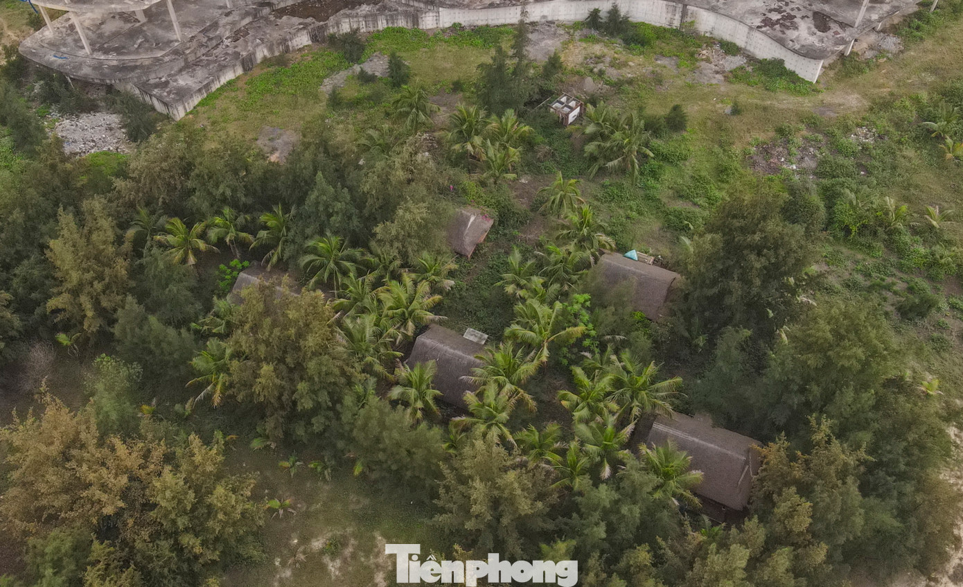 Một số căn nhà gỗ nghỉ dưỡng xây gạch bao quanh, mái lá nằm cạnh khu dự án từng được công nhân tận dụng làm chỗ nghỉ nay bị bỏ hoang, cỏ mọc um tùm và không bóng người qua lại.