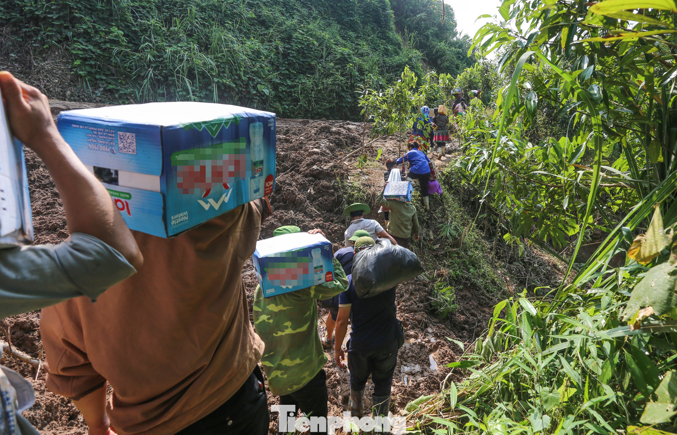 “Mỗi ngày em đi 2 chuyến, gùi được khoảng 20kg hàng hóa vào cho người dân. Kết thúc một ngày đi bộ gần 40, khi về đến nhà em lăn ra ngủ, đôi chân rã rời. Nhưng vì người dân gặp hoạn nạn, sáng sớm em lại cố dậy sớm, tiếp tục ra trung tâm xã gùi hàng vào cho dân”, Mô tâm sự. Trong hình, thanh niên địa phương mang nhu yếu phẩm vượt qua khu vực sạt lở để đưa vào tiếp tế cho người dân vùng sạt lở.