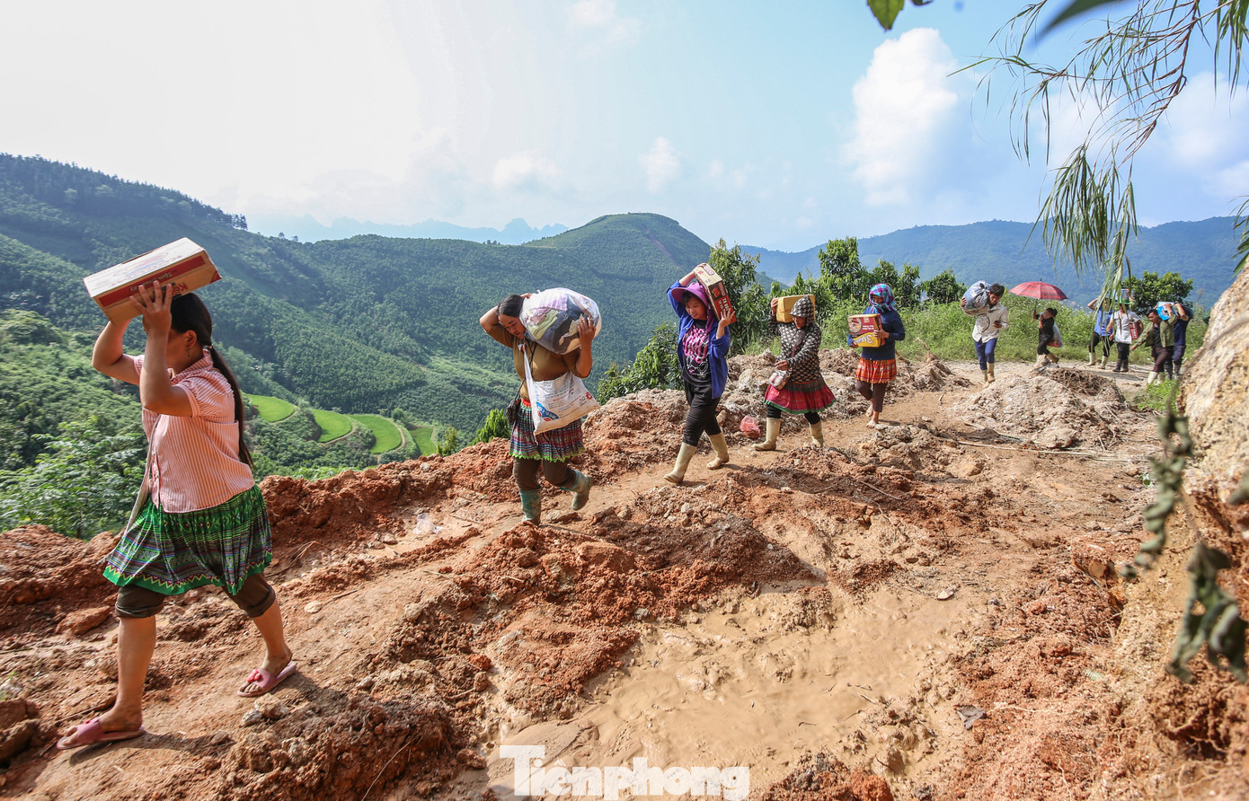 “Mỗi ngày em đi 2 chuyến, gùi được khoảng 20kg hàng hóa vào cho người dân. Kết thúc một ngày đi bộ gần 40, khi về đến nhà em lăn ra ngủ, đôi chân rã rời. Nhưng vì người dân gặp hoạn nạn, sáng sớm em lại cố dậy sớm, tiếp tục ra trung tâm xã gùi hàng vào cho dân”, Mô tâm sự. Trong hình, thanh niên địa phương mang nhu yếu phẩm vượt qua khu vực sạt lở để đưa vào tiếp tế cho người dân vùng sạt lở.