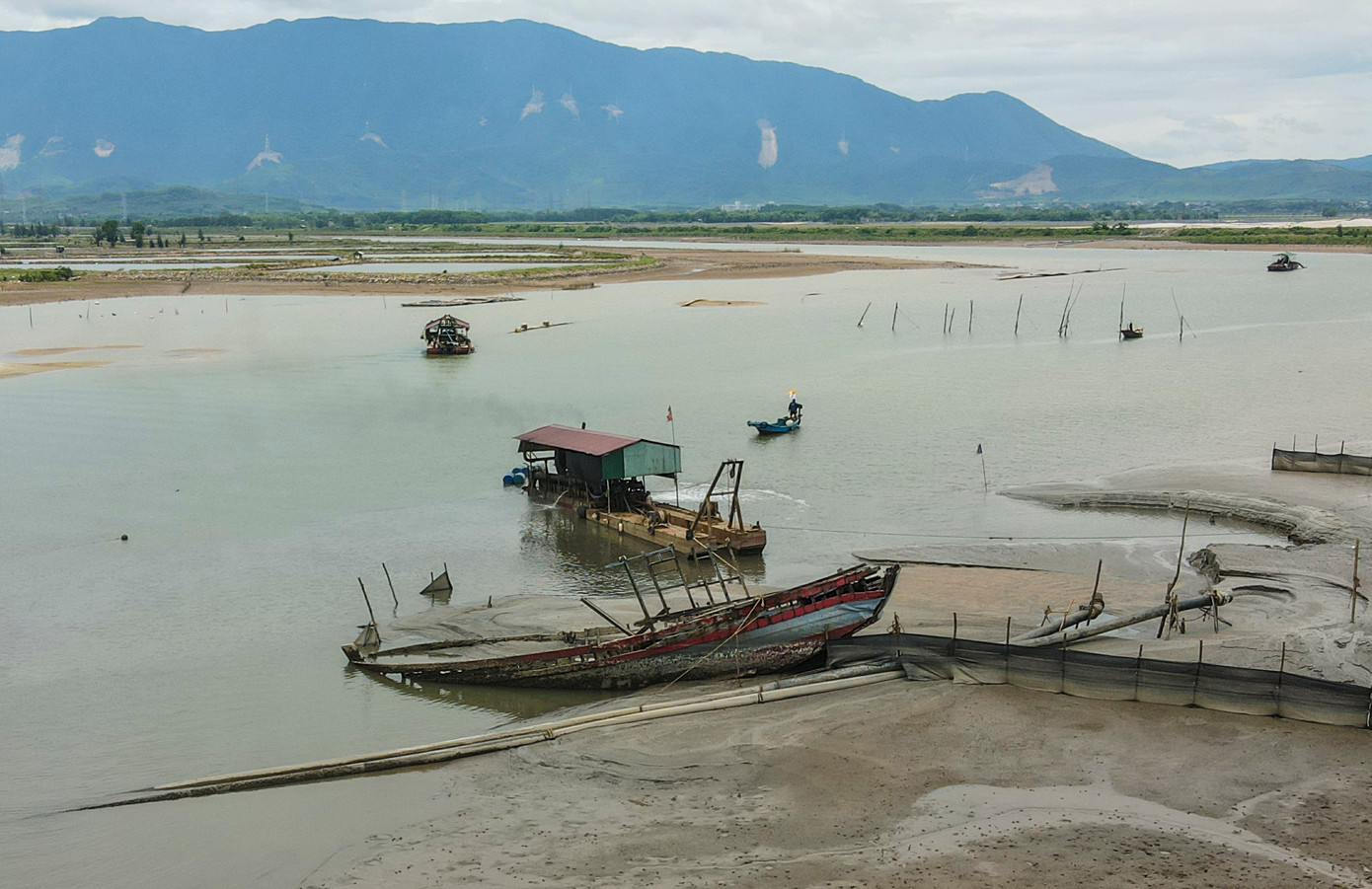 Cách đó không xa là tàu cá ngư dân bị hư hỏng, mục nát nằm dọc luồng lạch sông.