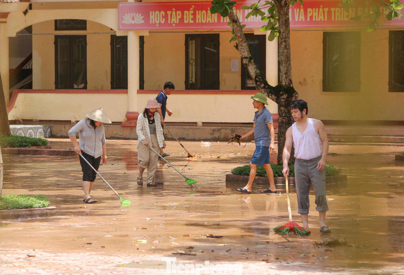 Thầy cô giáo Trường THCS Mỹ Duệ (xã Cẩm Duệ) dọn dẹp bùn đất khi lũ rút.