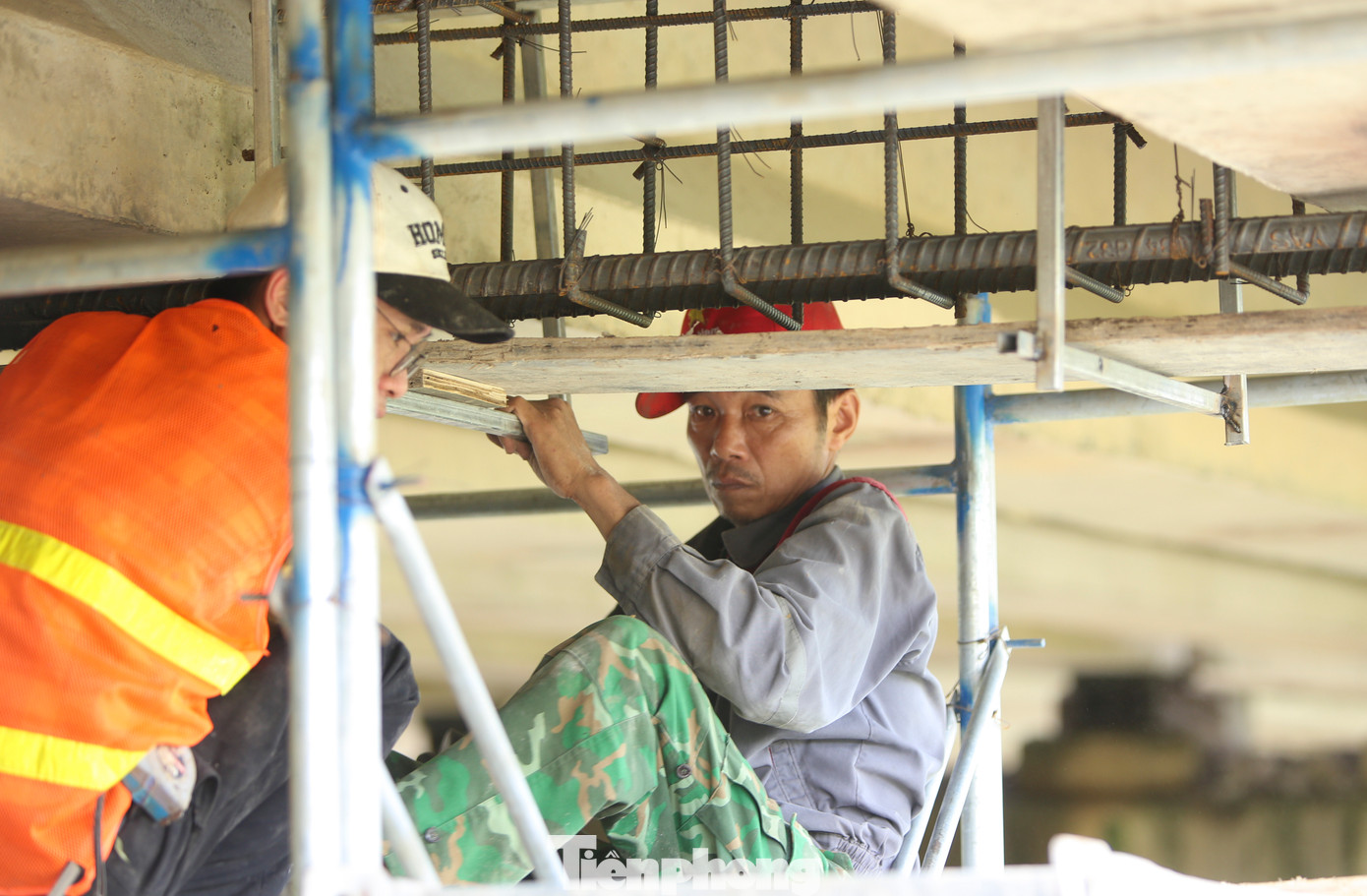 Phía dưới mố cầu bị hư hỏng, các công nhân đang bổ sung thêm dầm ngang giữa các nhịp cầu và sửa chữa đầu dầm bị vỡ bê tông.