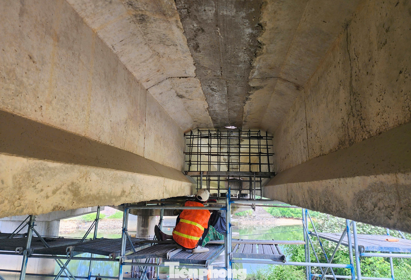 Phía dưới mố cầu bị hư hỏng, các công nhân đang bổ sung thêm dầm ngang giữa các nhịp cầu và sửa chữa đầu dầm bị vỡ bê tông.