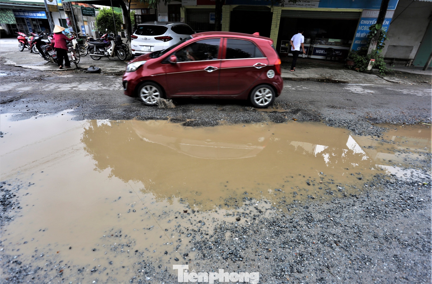 "Nhiều vị trí bị bong tróc thành từng vũng sâu, ngày nắng thì bụi bặm, ngày mưa nước ngập nên phương tiện qua lại gặp khó khăn, nguy hiểm. Ngành chức năng đôi lần rải đá bây trám các ổ voi nhưng đó chỉ là biện pháp tạm thời, cần có dự án nâng cấp để cứu con đường này", anh Chiến (xã Khánh Vĩnh Yên), chia sẻ. Trong ảnh là cảnh người và phương tiện giao thông gặp khó khi qua vị trí hư hỏng ở xã Khánh Vĩnh Yên, huyện Can Lộc.