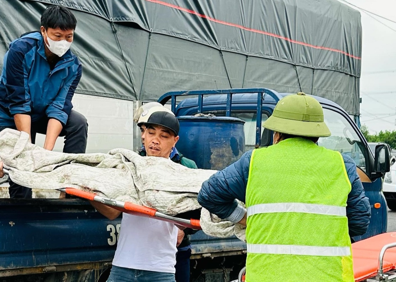 Người dân hỗ trợ đưa thi thể tài xế ô tô tải ra khỏi cabin.