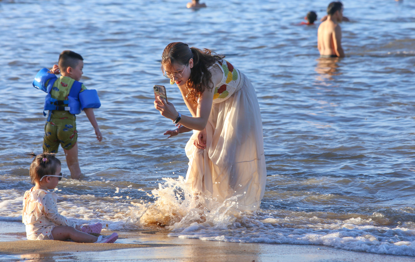 Một số bạn trẻ khác vui vẻ check-in trên bờ hoặc hòa mình vào làn nước trong xanh, mát rượi ven bãi cát mịn.