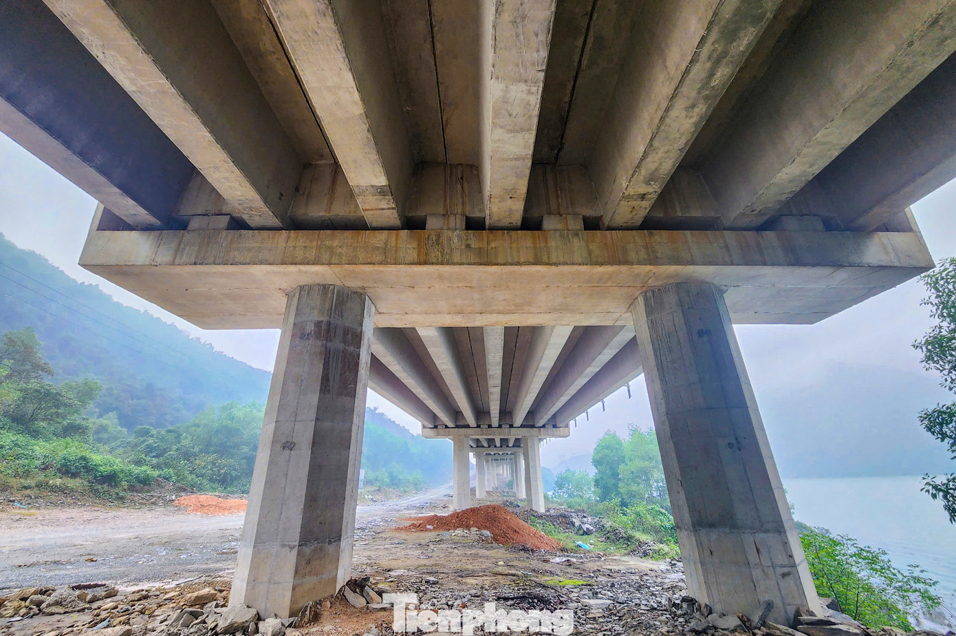 “Thời tiết những ngày cuối năm mưa liên tục, độ ẩm cao nên việc thảm nhựa mặt cầu phải chờ ngày nắng ấm. Công nhân đang lắp đặt lan can, dải phân cách và các vị trí tiếp nối mặt cầu”, đại diện đơn vị thi công cho hay. Trong hình là các cầu cạn có hàng chục nhịp cầu, mỗi trụ cầu cao 30-40m, lao dầm Super T chắc chắn.