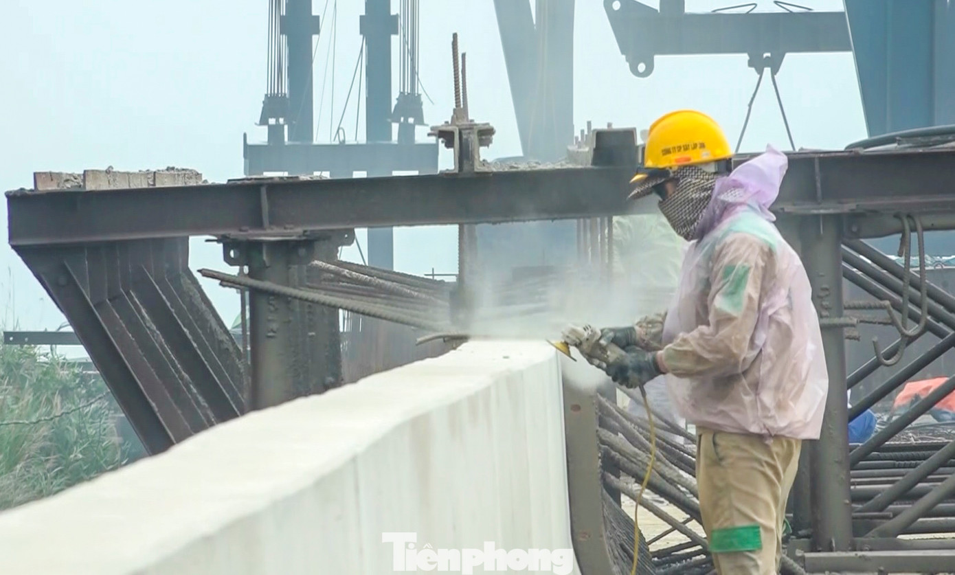 Hệ thống lan can, dải phân cách cứng được lắp đặt. Công nhân miệt mài thi công trên công trình.