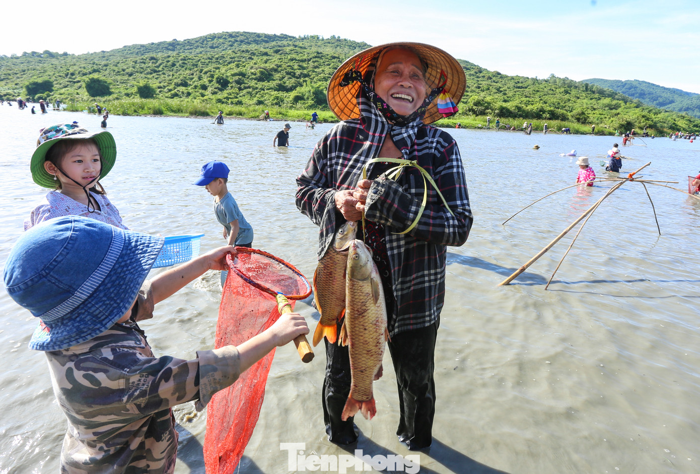 Người phụ nữ lớn tuổi cùng người thân đứng gần bờ để cất vó và may mắn bắt được những con cá chép, trắm khá to.