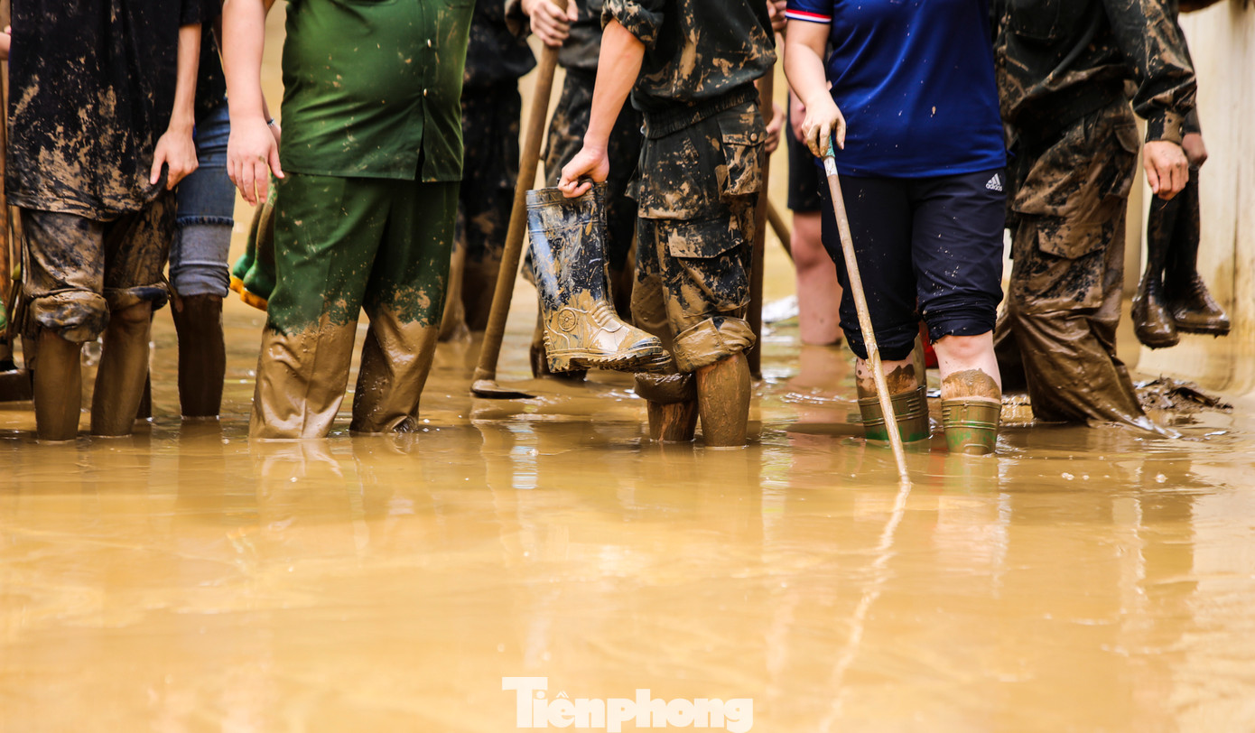 “Bùn quá dày nhưng anh em cố gắng dọn sớm trước khi khô sẽ khó khăn hơn”, chiến sĩ Hà Thanh Tứ cho hay. Trong hình, lớp bùn non dày gần đến đầu gối.