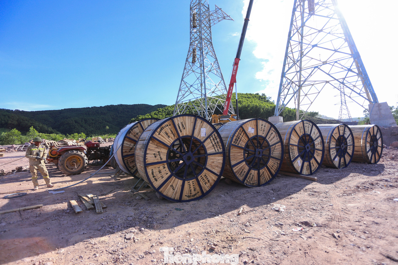 Sau giai đoạn dựng cột, đến nay các nhà thầu đang kéo dây cáp. Vật tư, thiết bị được đưa đến dưới chân cột. Mỗi cuộn dây dẫn có chiều dài 2.000-2.400m, nặng 5-6 tấn.