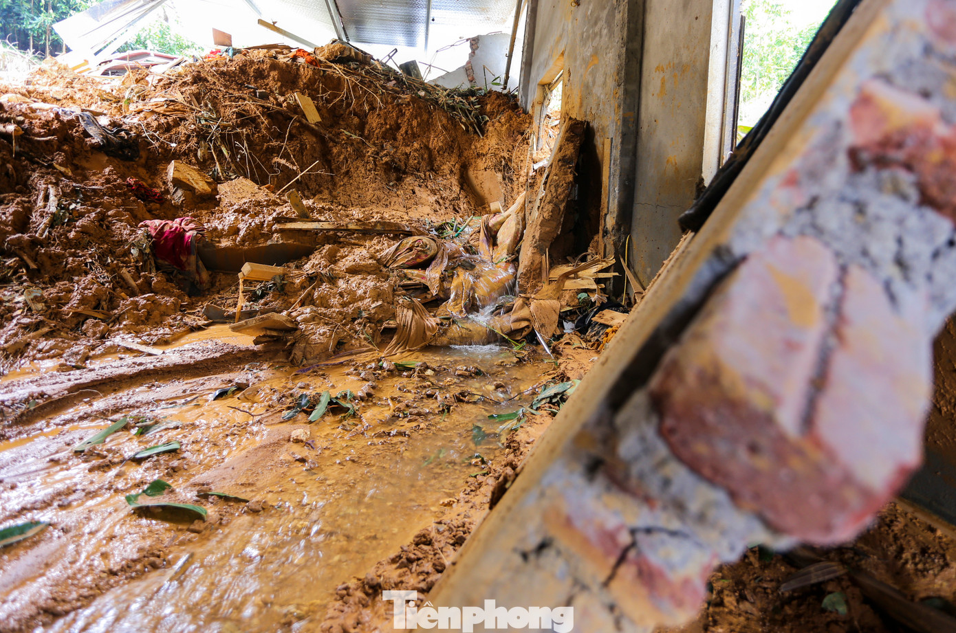 Những mảng tường xây gạch bị xô gãy. Dòng bùn đỏ vẫn chảy từ trên đồi qua căn nhà.