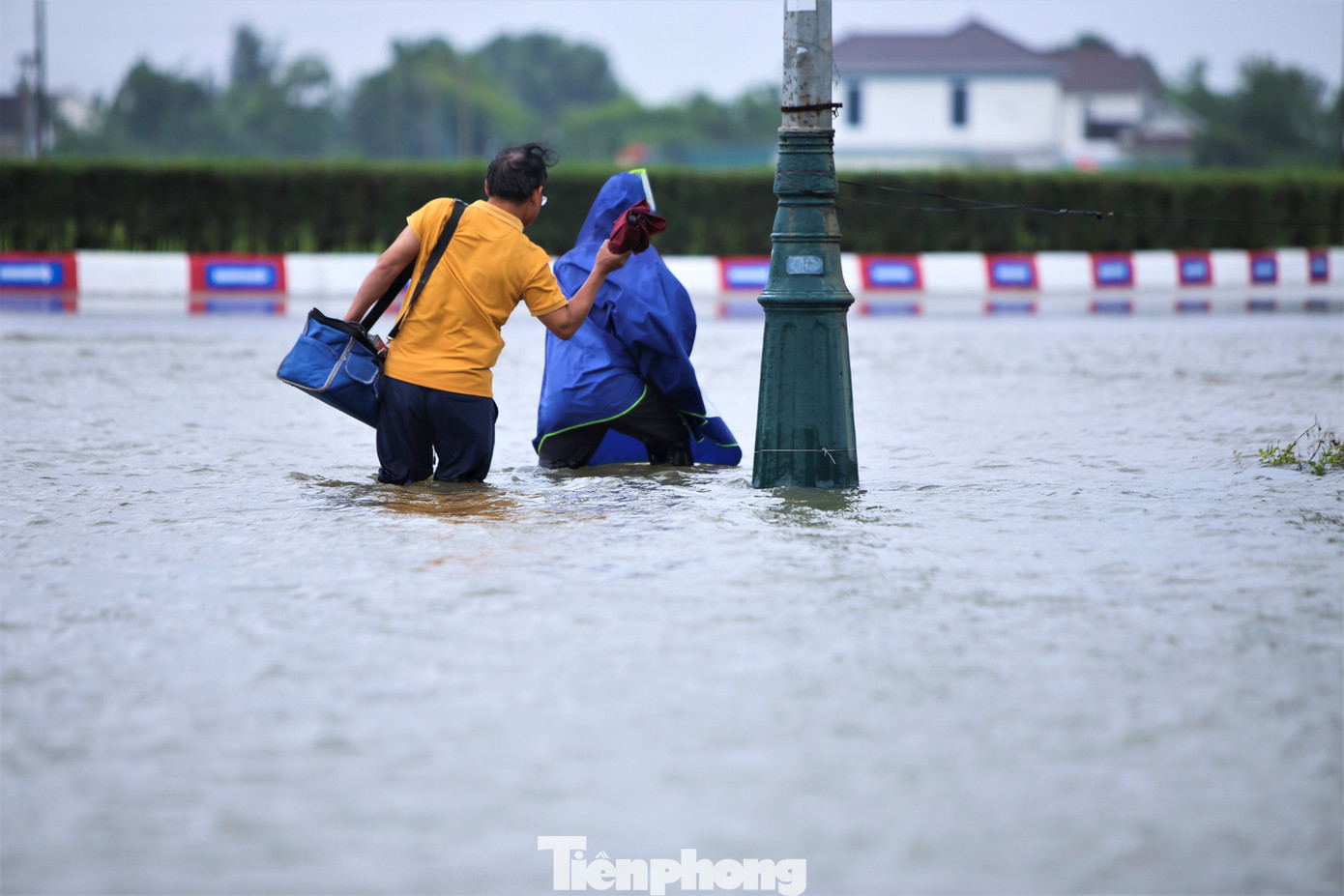 Người dân bì bõm lội nước để di chuyển ra khỏi vùng ngập lụt.