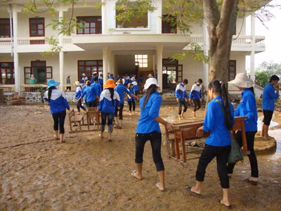 Lực lượng tình nguyện đang giúp chùi rửa bàn ghế ở trường tiểu học Quảng Minh B