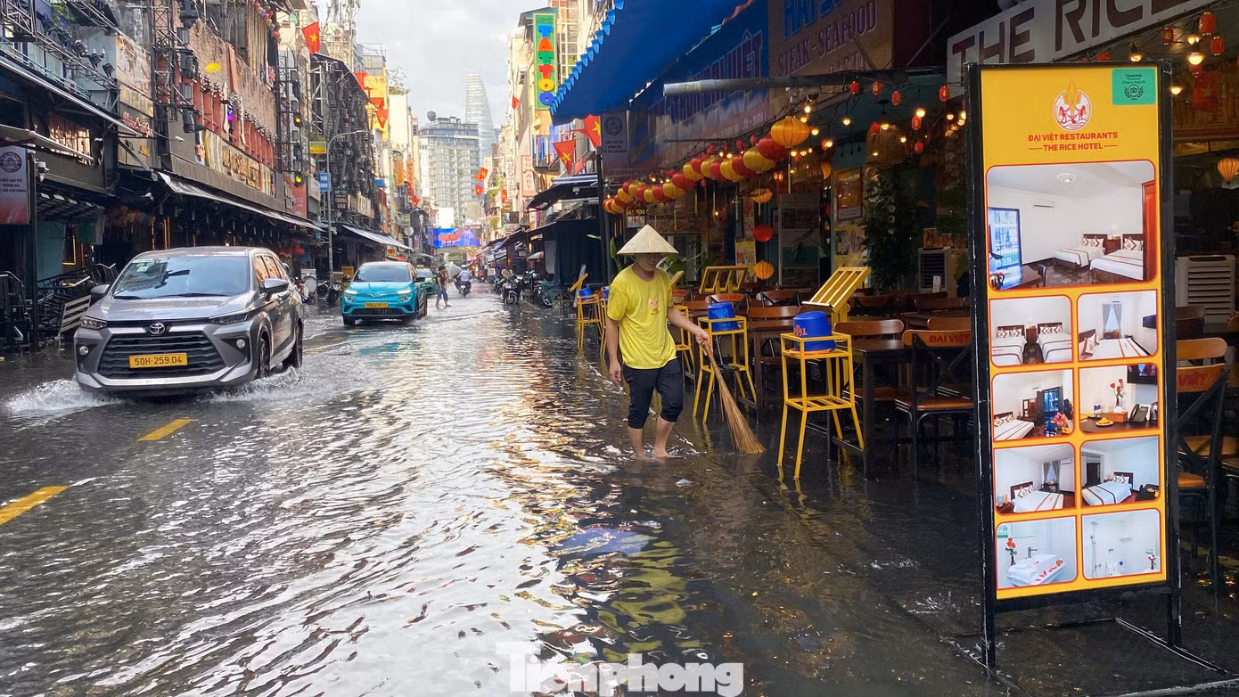 Nhân viên các hàng quán hai bên đường tất bật dọn dẹp, thu gom rác, khơi thông miệng cống để nước rút nhanh hơn.