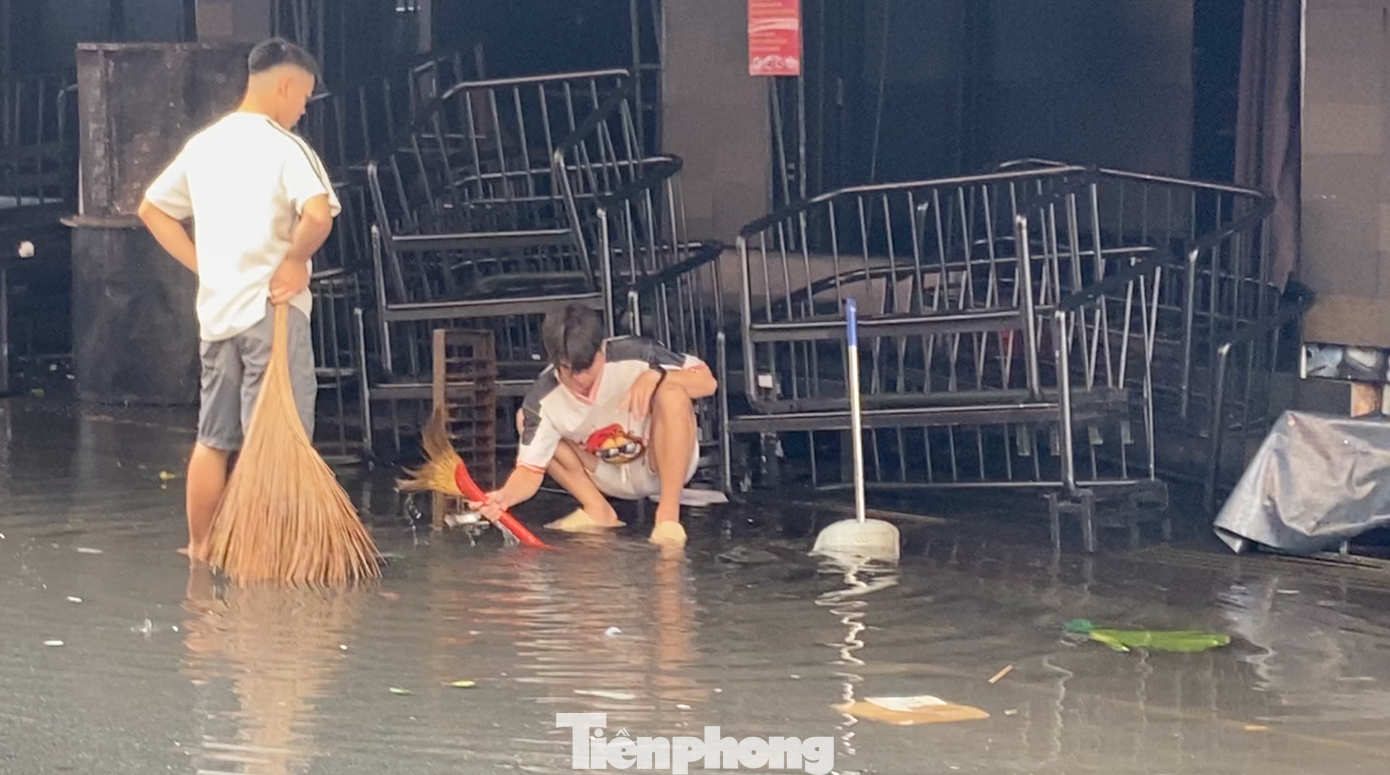 Nhân viên các hàng quán hai bên đường tất bật dọn dẹp, thu gom rác, khơi thông miệng cống để nước rút nhanh hơn. Nhân viên các hàng quán hai bên đường tất bật dọn dẹp, thu gom rác, khơi thông miệng cống để nước rút nhanh hơn.