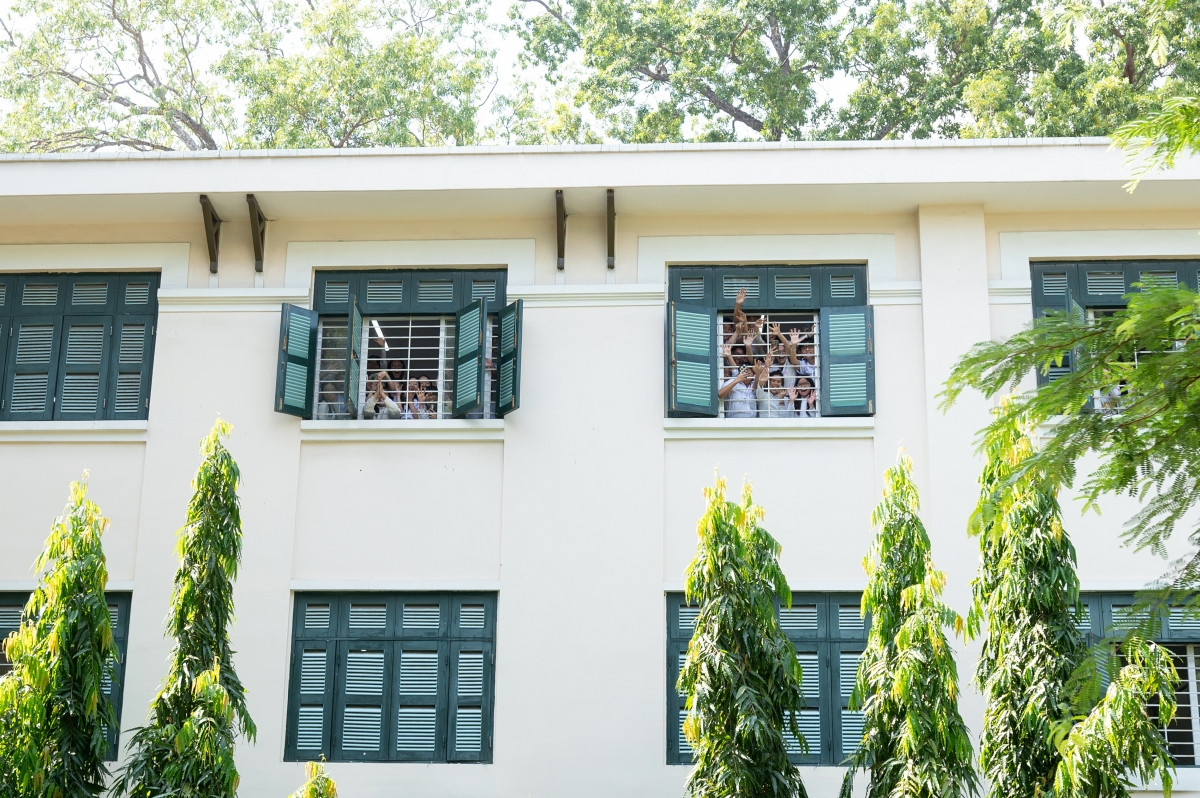 Học sinh tại một trường học vẫy tay chào Hoa hậu Thanh Thủy khi xe buýt của cô đi qua.