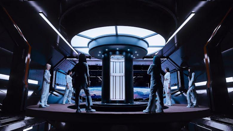 MV FIRST mở đầu với 6 thành viên hiện tại đứng trên một trạm vũ trụ, xung quanh một thang máy vận chuyển như đang chờ đợi điều gì đó hoặc ai đó. MV FIRST mở đầu với 6 thành viên hiện tại đứng trên một trạm vũ trụ, xung quanh một thang máy vận chuyển như đang chờ đợi điều gì đó hoặc ai đó.