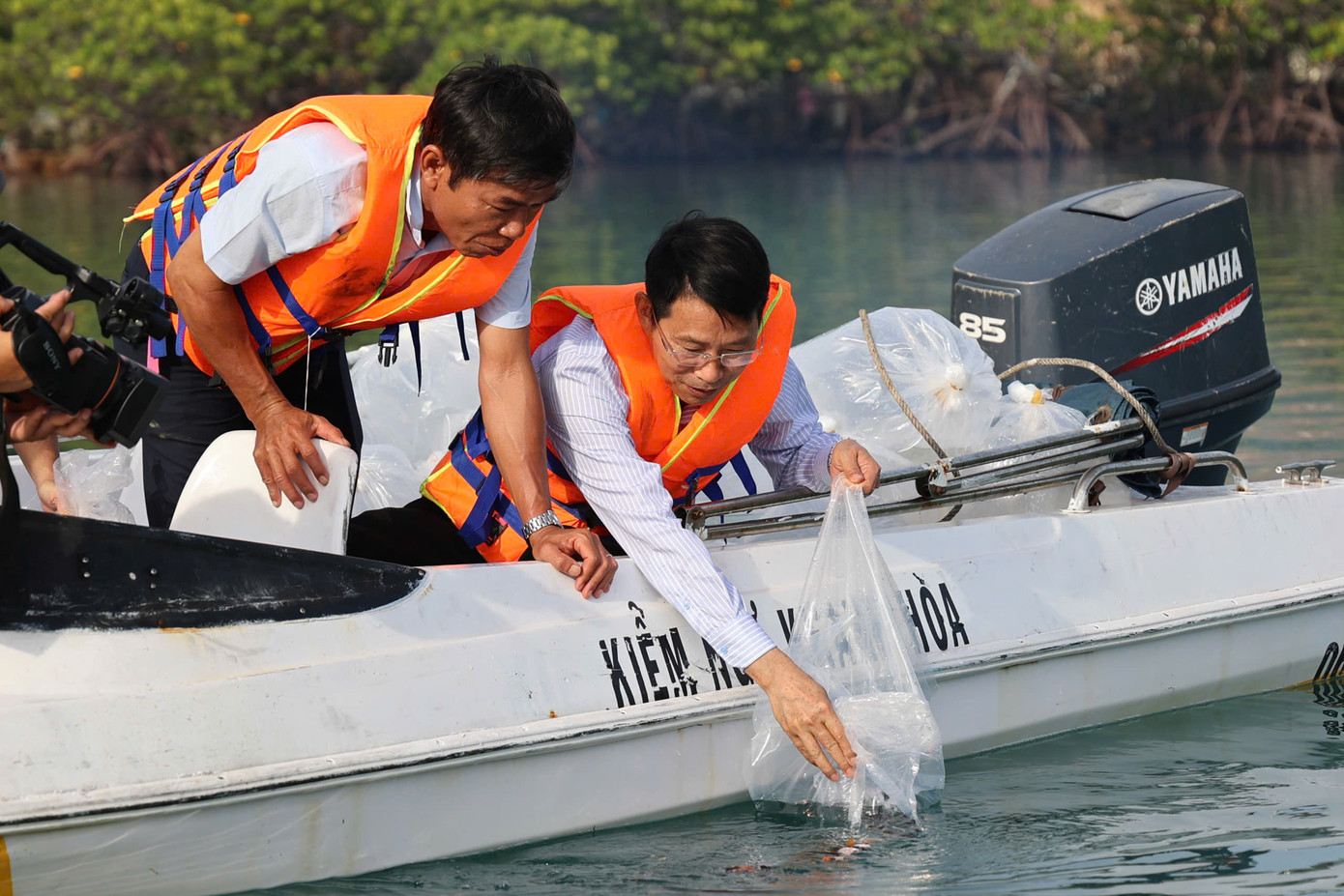 Ông Đinh Văn Thiệu (bên phải) tham gia thả cá tại khu vực Đầm Bấy, vịnh Nha Trang.