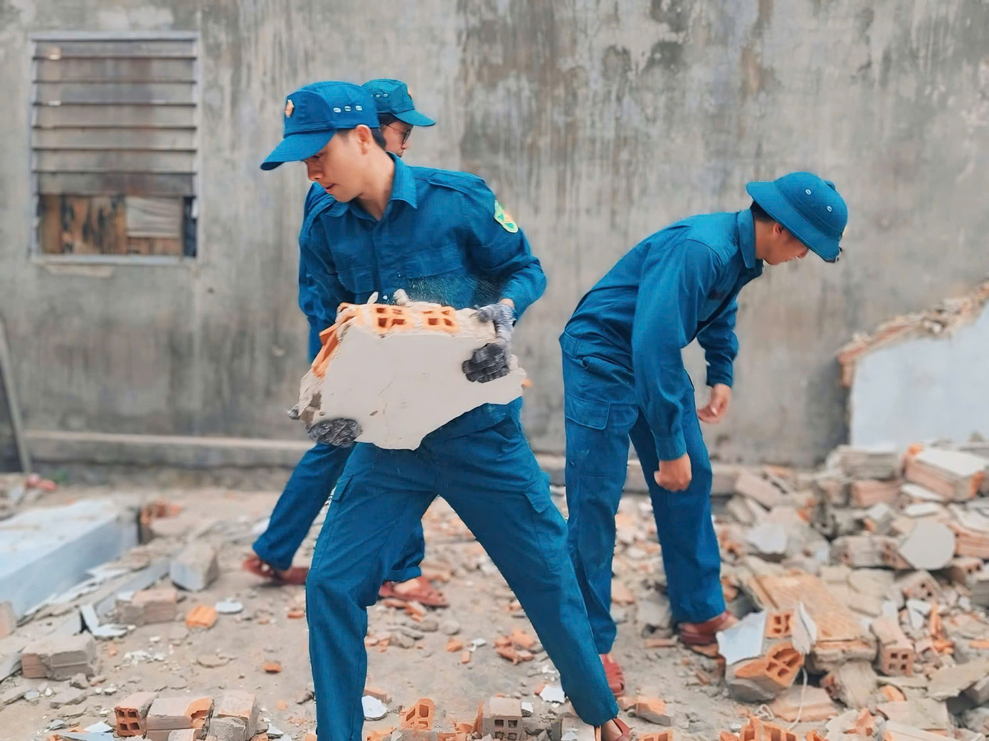 Nhóm thanh niên tất bật thu dọn sạch sẽ sau khi tháo dỡ mái, đập bỏ tường căn nhà cũ bị xuống cấp của bà Võ Thị Nguyệt ở tổ dân phố số 12, thị trấn Vạn Giã, huyện Vạn Ninh.