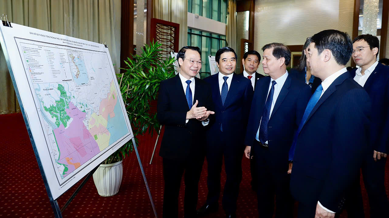 Bộ trưởng Bộ Tài nguyên và Môi trường (trái) giới thiệu với các đại biểu bản đồ quy hoạch tổng thể, sử dụng bền vững tài nguyên vùng bờ thời kỳ 2021-2025, tầm nhìn đến năm 2050.
