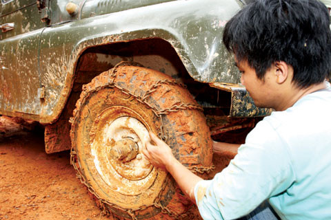 Sự khắc nghiệt của mùa mưa Tây Nguyên cùng vô vàn những gian nan cả khách quan và chủ quan không thể kể hết của người lính luôn hiện hữu trên mỗi cung đường. Chẳng thế mà khi đi khảo sát công trường của Công ty TNHH MTV 36.55, Tổng công ty 36 ở gói thầu đường vào Đồn Biên phòng 669 Đắk Nhoong, Tiến sĩ Trần Hồng Mai - Viện trưởng Viện Kinh tế Xây dựng (Bộ Xây dựng) nhận xét rằng: “Con đường này chỉ có sự bền bỉ, dẻo dai, sức chịu đựng gian khổ và đặc biệt là đức hy sinh của người lính mới có thể làm được. Mỗi chuyến đi thực tế càng làm chúng tôi thêm cảm phục nhiệm vụ mở đường của bộ đội thời bình”. Trong ảnh: Để vượt qua đoạn đường lầy lội, trơn trượt, lính thợ Công ty TNHH MTV 36.55 cũng như nhiều đơn vị làm đường tuần tra phải sử dụng sáng kiến quấn xích sắt vào bánh xe U-oát để tăng độ bám đường mới hy vọng vào được tuyến