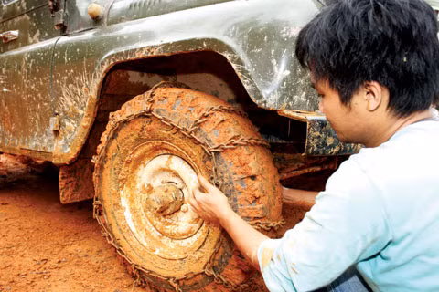 Sự khắc nghiệt của mùa mưa Tây Nguyên cùng vô vàn những gian nan cả khách quan và chủ quan không thể kể hết của người lính luôn hiện hữu trên mỗi cung đường. Chẳng thế mà khi đi khảo sát công trường của Công ty TNHH MTV 36.55, Tổng công ty 36 ở gói thầu đường vào Đồn Biên phòng 669 Đắk Nhoong, Tiến sĩ Trần Hồng Mai - Viện trưởng Viện Kinh tế Xây dựng (Bộ Xây dựng) nhận xét rằng: “Con đường này chỉ có sự bền bỉ, dẻo dai, sức chịu đựng gian khổ và đặc biệt là đức hy sinh của người lính mới có thể làm được. Mỗi chuyến đi thực tế càng làm chúng tôi thêm cảm phục nhiệm vụ mở đường của bộ đội thời bình”. Trong ảnh: Để vượt qua đoạn đường lầy lội, trơn trượt, lính thợ Công ty TNHH MTV 36.55 cũng như nhiều đơn vị làm đường tuần tra phải sử dụng sáng kiến quấn xích sắt vào bánh xe U-oát để tăng độ bám đường mới hy vọng vào được tuyến