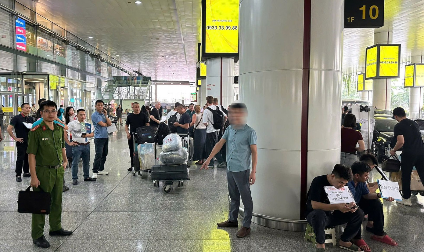 Lực lượng chức năng và đối tượng mời chào vị du khách Đài Loan đi xe trái phép tại cột số 10 - nhà ga quốc tế T2 Nội Bài. Ảnh: NIA.