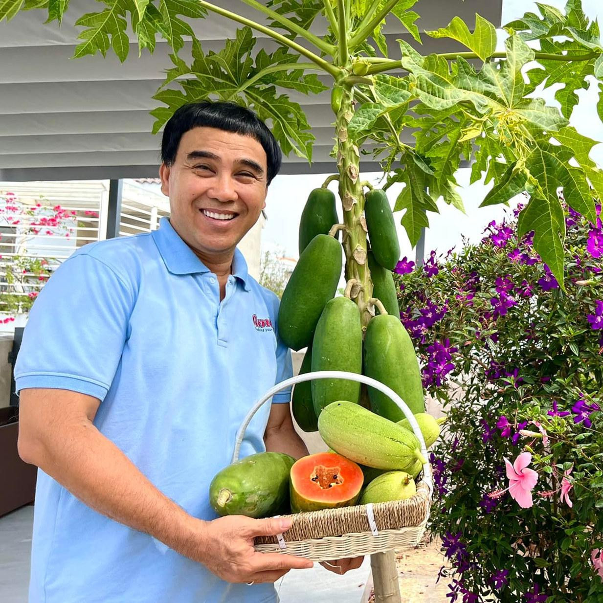 MC Quyền Linh tươi cười bên cây sai trĩu quả.