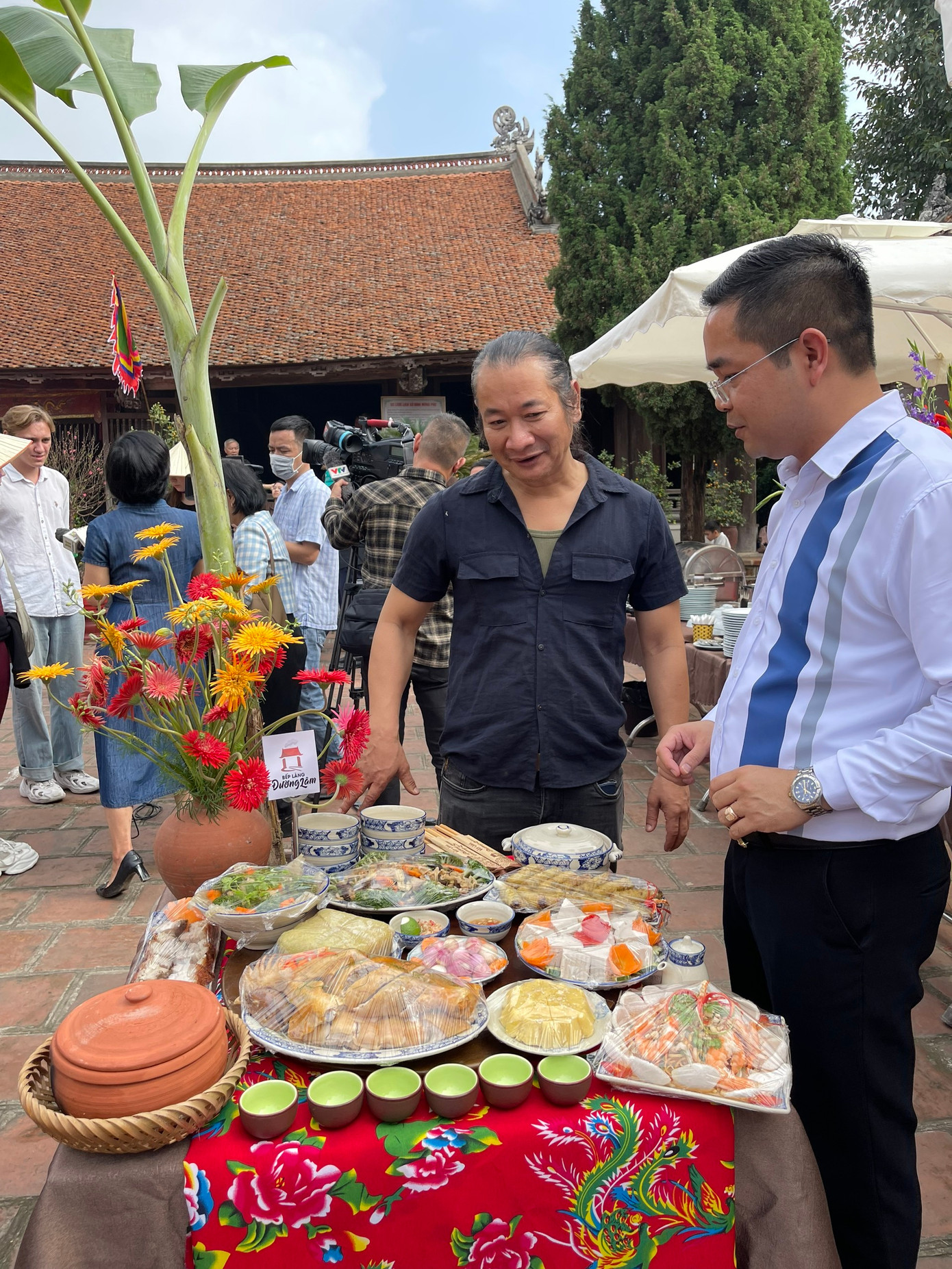 Ông Nguyễn Đăng Thạo (phải) - Trưởng Ban quản lý Di tích Làng cổ Đường Lâm - tại không gian trưng bày mâm cỗ Tết. Ông cho biết: “Tết làng Việt tạo hiệu ứng kích cầu du lịch Làng cổ Đường Lâm nói riêng và thị xã Sơn Tây nói chung, để đón khách đến tham quan, trải nghiệm văn hóa dịp Tết và du Xuân Giáp Thìn. Năm 2023, ở lần thứ hai tổ chức, chương trình thu hút khoảng 1,5 vạn du khách. Năm nay, chúng tôi dự kiến con số có thể lên tới 2,5 vạn”.