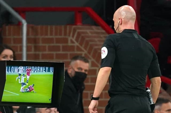 Trọng tài "check" VAR trong một trận đấu trên sân Old Trafford ở Giải Ngoại hạng Anh. Ảnh: PA.