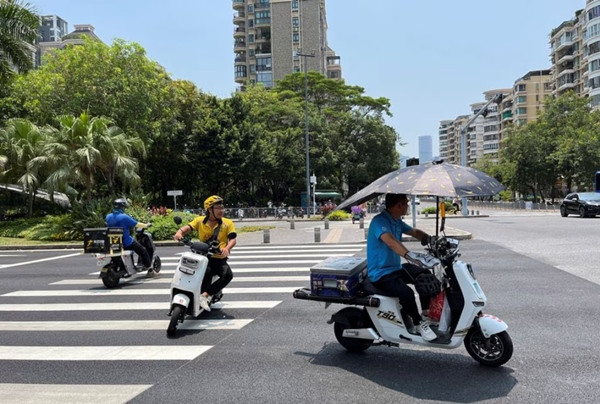 Những người giao hàng đi xe máy dưới cái nóng đã ở mức cảnh báo màu vàng ở Thâm Quyến (Trung Quốc) vào ngày 2/6/2023. Ảnh: David Kirton/ Reuters.