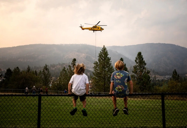 Hai bạn nhỏ ngồi xem máy bay trực thăng chữa cháy. Ảnh: Justine Boulin/ CBC.