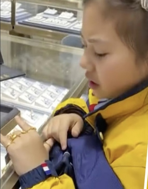 Bé gái đeo thử nhẫn trước khi chọn một chiếc cho mẹ. Ảnh: Douyin.